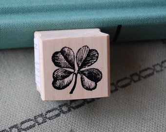 May include: A wooden stamp with a black and white illustration of a four-leaf clover.