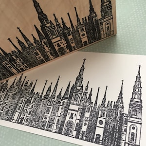 May include: Black and white illustration of a city skyline with many tall buildings, each with a pointed roof. The buildings are arranged in a row, with the tallest building in the center.