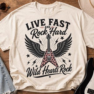 May include: Cream-colored t-shirt with the text "LIVE FAST and Rock Hard Wild Hearts Rock". The graphic features a guitar with pink leopard print, black wings, stars, and lightning bolts. A guitar and sunglasses are visible.