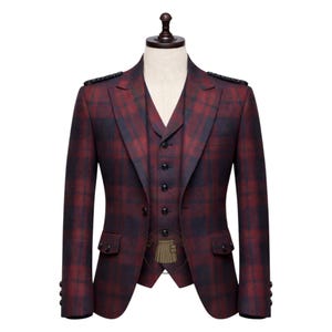 Puede incluir: Un traje de tres piezas con un patrón de cuadros, exhibido en un maniquí. El traje presenta una chaqueta, un chaleco y un pantalón en una combinación de colores burdeos y azul marino. La chaqueta tiene dos bolsillos delanteros y detalles decorativos en los hombros. El chaleco tiene una botonadura frontal.