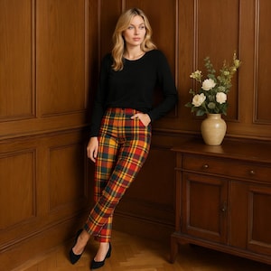 May include: A woman wearing a black long-sleeve shirt and plaid pants. The pants feature a colorful plaid pattern in red, yellow, green, and navy blue. She is wearing black heels.