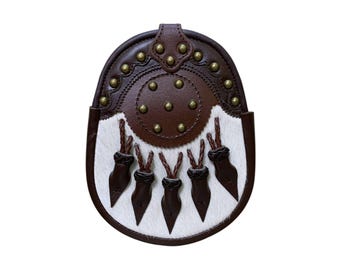 May include: A brown leather sporran with a white fur front. The sporran has a rounded top with brass studs and decorative stitching. Five brown leather tassels hang from the bottom.