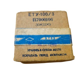 May include: A rectangular, tan-colored box with blue and white accents. The box has text in a foreign language, including the dimensions 30x55x9. The box is wrapped with a blue and white band.