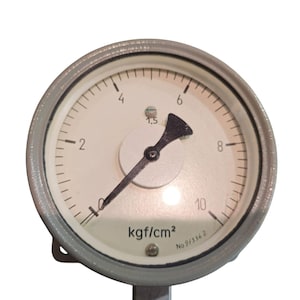 Può includere: Un manometro rotondo con quadrante bianco e cassa in metallo grigio. L'indicatore mostra numeri da 0 a 10, con un ago nero che indica la pressione. Il testo "kgf/cm²" è stampato sul quadrante.