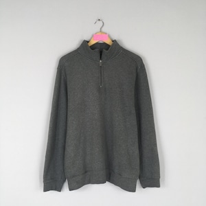 May include: A charcoal gray sweatshirt with a quarter-zip closure. The long-sleeved top has a high collar and is hanging on a wooden hanger. The fabric appears to be a soft, knit material.