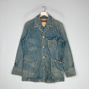 May include: A vintage denim jacket with a light blue wash, featuring a classic collar, gold buttons, and multiple pockets. The jacket is hanging on a hanger, showcasing its worn-in texture and design.
