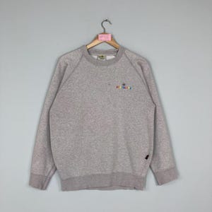 May include: A heather gray sweatshirt with the embroidered text "BODY GLOVE" in rainbow colors. The long-sleeved crew neck sweatshirt has a ribbed collar, cuffs, and hem. A small black tag is sewn on the lower left side.