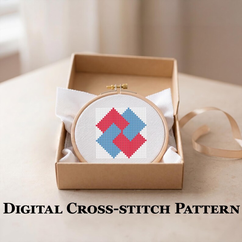 May include: A cross-stitch pattern in a wooden hoop, featuring a geometric design of interlocking red and blue squares on a white background. The hoop is presented in a brown cardboard box with white fabric. The text "DIGITAL CROSS-STITCH PATTERN" is at the bottom.