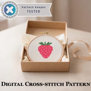 May include: A cross-stitch pattern of a strawberry in a wooden hoop, presented in a cardboard box. The strawberry is pink with white dots and green leaves. The text "Pattern Keeper TESTED" is at the top, and "DIGITAL CROSS-STITCH PATTERN" is at the bottom.