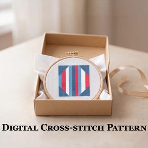 May include: A cross-stitch pattern in a wooden hoop, featuring a geometric design with red, blue, and white sections. The hoop is presented in a brown cardboard box with white fabric. The text "DIGITAL CROSS-STITCH PATTERN" is at the bottom.