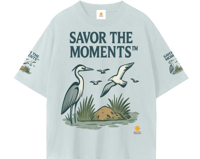 Featured listing image: Coastal vibe, Unisex Seamless T‑Shirt, heron graphic, sea oats, marsh birds, relaxed beach‑inspired summer gift for nature lovers.