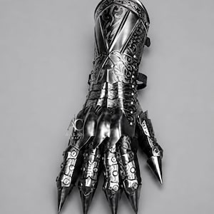 Puede incluir: Un guantelete met&aacute;lico con grabados de volutas intrincados y placas de dedos puntiagudas. La pieza de armadura muestra un acabado oscuro y pulido con remaches visibles y el texto AC AALAM CRAFT grabado en el lateral de la secci&oacute;n de la mano.