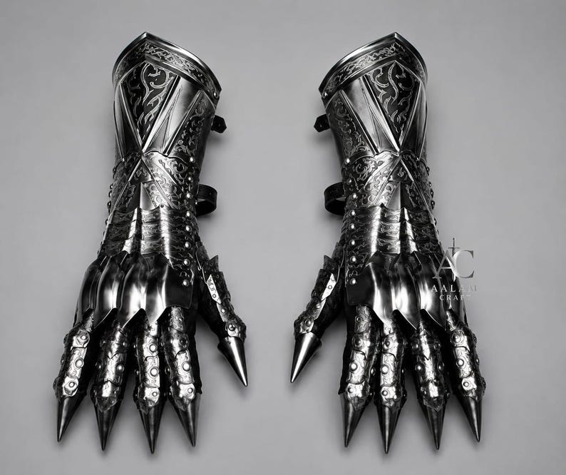 Puede incluir: Un par de guanteletes de metal oscuro con intrincados patrones de volutas grabados en los pu&ntilde;os y placas de dedos articuladas que terminan en puntas afiladas. La superficie met&aacute;lica tiene un acabado pulido con remaches visibles y el texto AC AALAM CRAFTS.