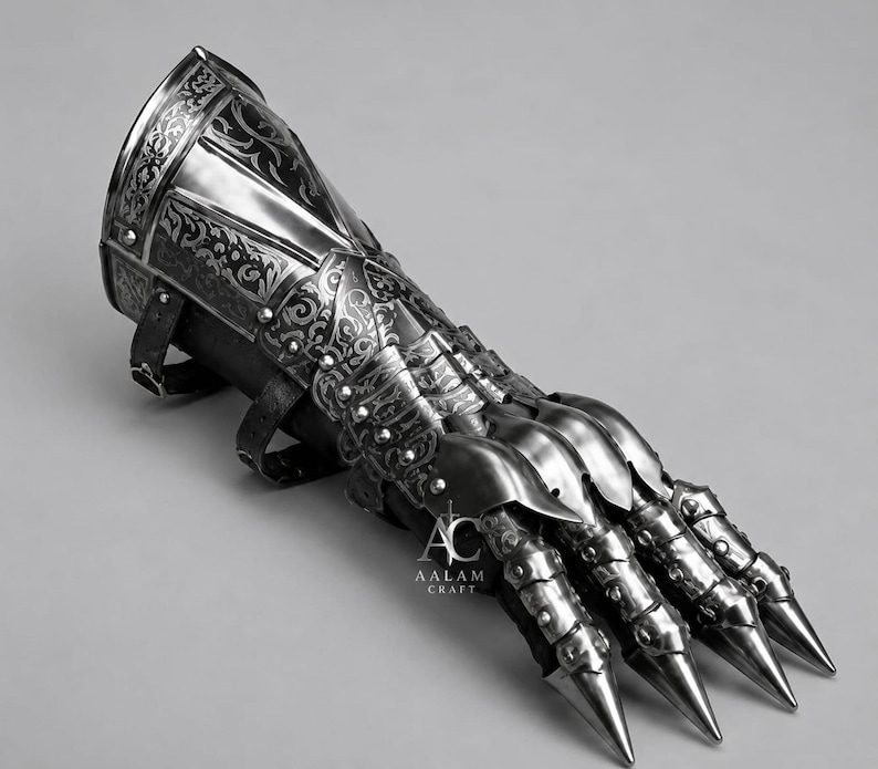 Puede incluir: Un guantelete de acero pulido con intrincados patrones florales grabados, placas articuladas para los dedos y puntas afiladas. La armadura de metal incluye correas de cuero negro para sujetar y muestra el texto AALAM CRAFT con un icono de espada.