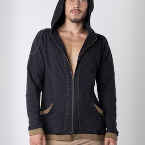 Puede incluir: Una sudadera con capucha azul oscuro con cierre de cremallera y ribetes marrones. La sudadera tiene un corte holgado y un estilo casual.