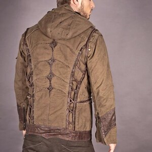 May include: A brown hooded jacket with a unique design featuring leather straps and metal accents. The jacket has a distressed look and is made of a durable fabric.