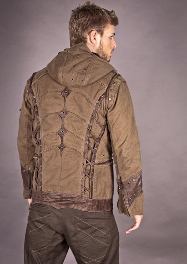 May include: A brown hooded jacket with a unique design featuring leather straps and metal accents. The jacket has a distressed look and is made of a durable fabric.