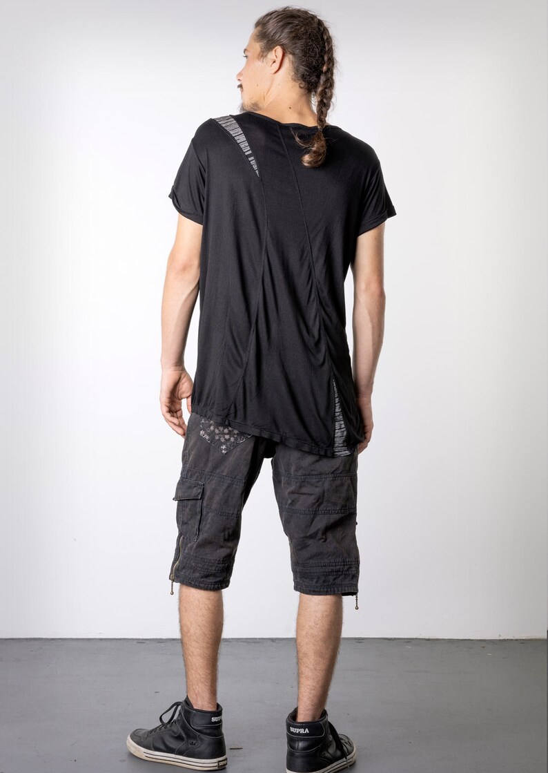 May include: Black t-shirt with a unique design, paired with dark gray cargo shorts. The shorts feature multiple pockets and a distressed look. The outfit is completed with black high-top sneakers.