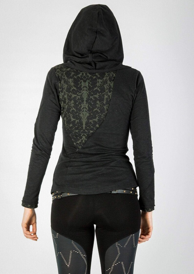 May include: Black long-sleeved shirt with a green patterned design on the back. The shirt has a hood and a black belt.