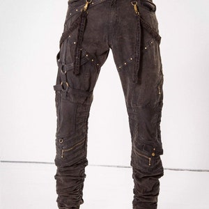May include: Dark brown cargo pants with multiple straps and buckles, accented with gold hardware and studs. The pants have a distressed look and are designed for a casual, edgy style.