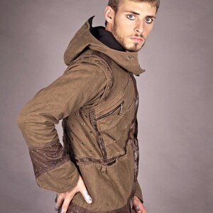 May include: A brown hooded jacket with a distressed look, featuring leather accents and multiple pockets. The jacket has a zip closure and a drawstring hood.