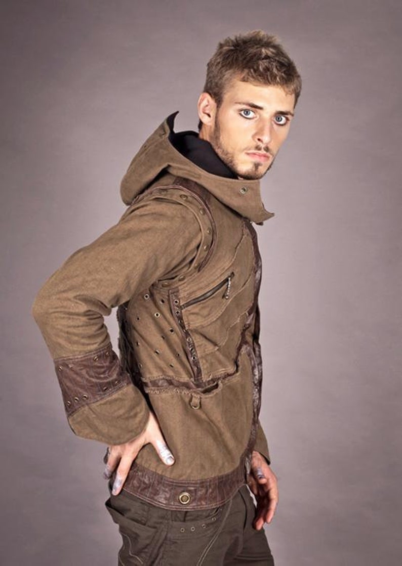 May include: A brown hooded jacket with a distressed look, featuring leather accents and multiple pockets. The jacket has a zip closure and a drawstring hood.