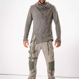 May include: A gray long-sleeved shirt with a cowl neck and a gray and green pair of pants with a unique design featuring straps and buckles.