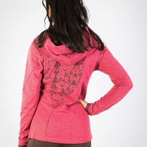 May include: A pink hooded sweatshirt with a floral design on the back. The sweatshirt has long sleeves and a relaxed fit.