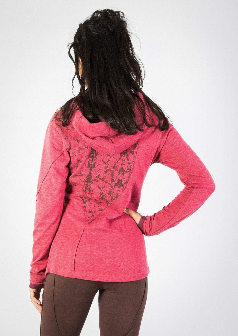 May include: A pink hooded sweatshirt with a floral design on the back. The sweatshirt has long sleeves and a relaxed fit.