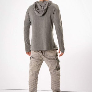 May include: A gray long-sleeved hooded shirt with a relaxed fit and a pair of gray cargo pants with multiple pockets and straps.