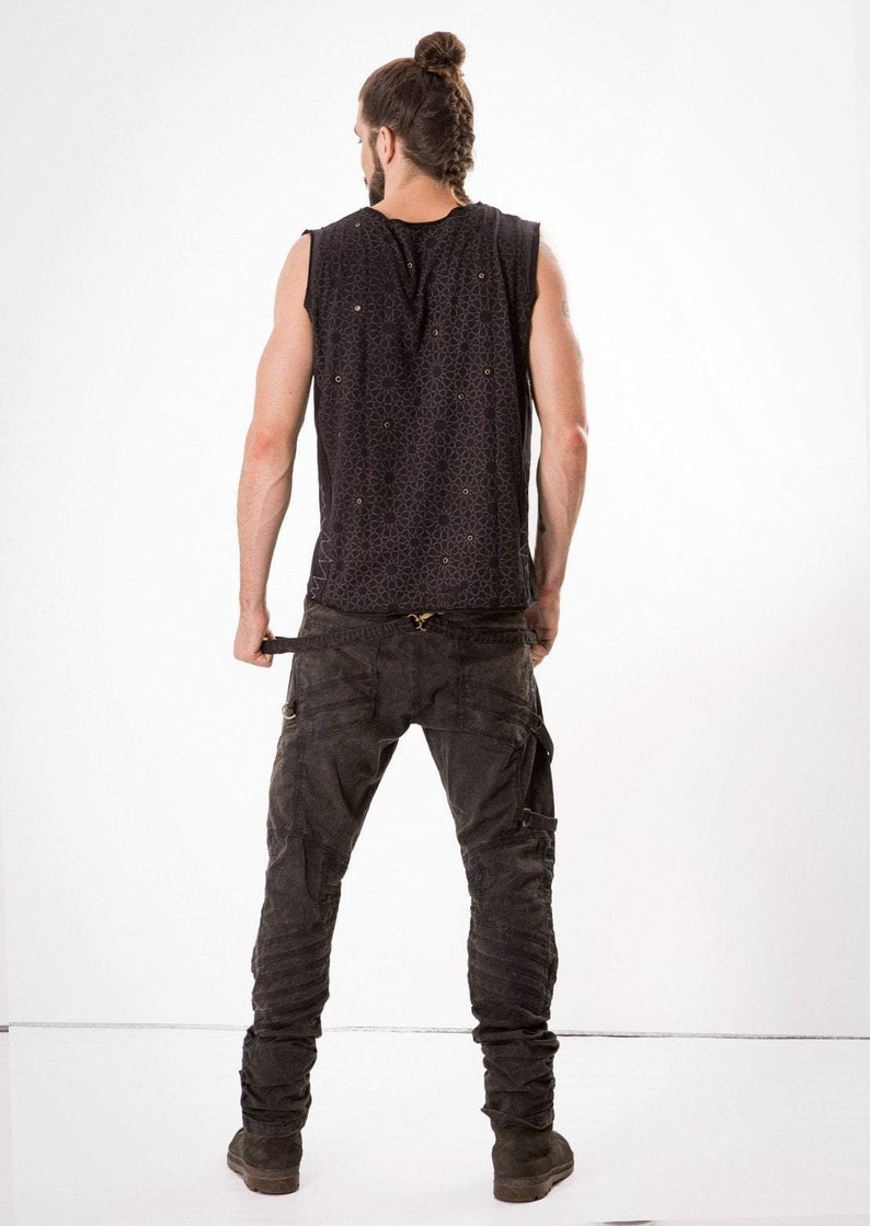 May include: A person wearing a black sleeveless shirt with a geometric pattern and black cargo pants with multiple buckles and straps.
