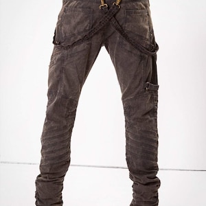 May include: Dark gray denim jeans with multiple stitched panels and a unique suspender system with metal hardware.