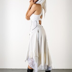 May include: A white dress with a lace trim and a white head scarf. The dress has a corset-style bodice and a flowing skirt.