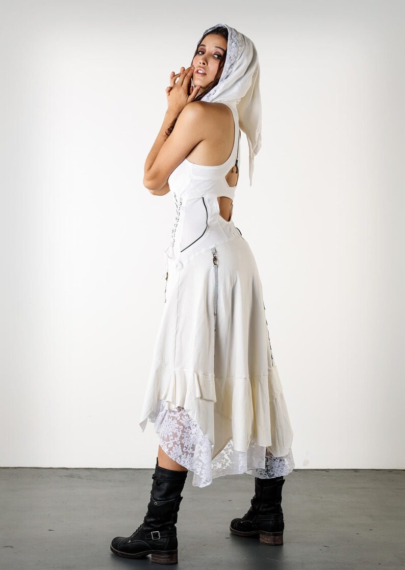 May include: A white dress with a lace trim and a white head scarf. The dress has a corset-style bodice and a flowing skirt.