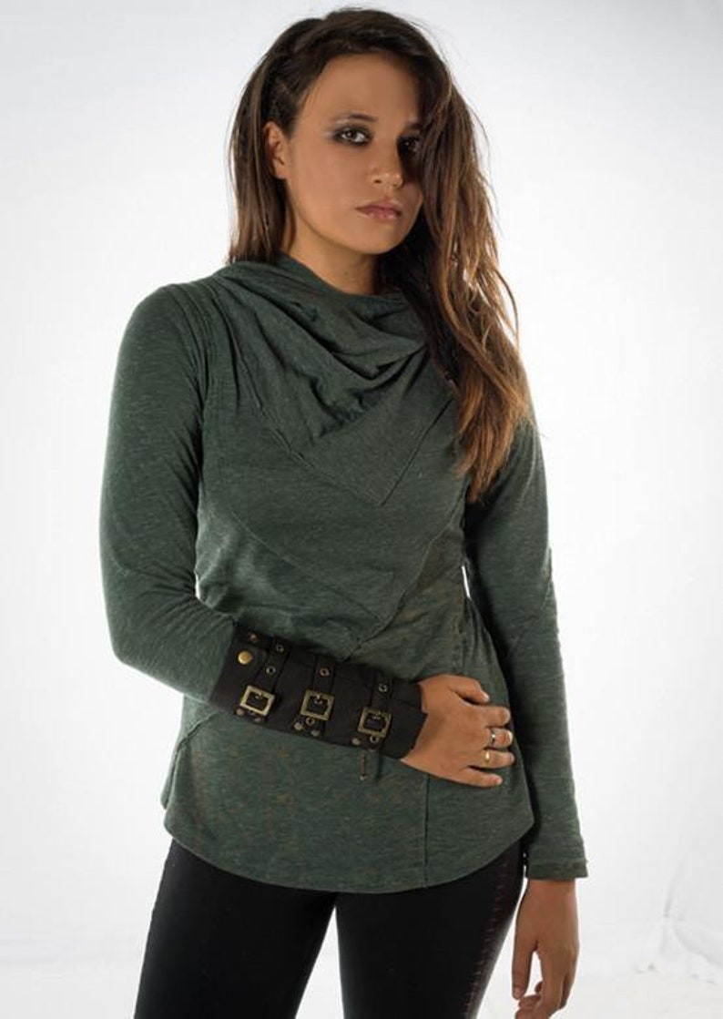 May include: A green long-sleeved shirt with a cowl neck and a black leather cuff with gold buckles on the left wrist.