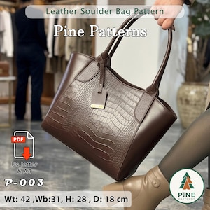 Puede incluir: Bolso de hombro de cuero marrón con estampado de cocodrilo. El bolso tiene dos asas y una pequeña etiqueta. El texto "Leather Soulder Bag Pattern" y "Pine Patterns" son visibles. Medidas: An: 42 cm, An: 31 cm, Al: 28 cm, Pr: 18 cm.