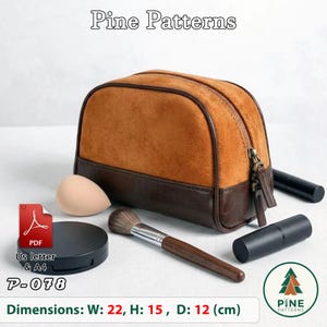 Peut inclure: Une trousse de toilette en daim marron et cuir marron foncé avec une fermeture éclair. La trousse est entourée d'une éponge à maquillage, d'un pinceau à maquillage avec un manche en bois et deux tubes noirs. Texte : Pine Patterns P-078.