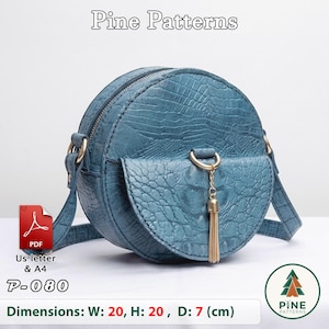 May include: A round, teal-coloured crossbody bag with a textured crocodile-skin pattern. It features a top zip, a front flap pocket with a gold-toned ring and tassel charm, and side strap attachments. Text includes Pine Patterns, P-080, and 20 x 20 x 7 cm.
