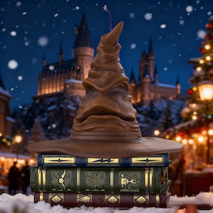 Könnte beinhalten: Ein brauner Sprechhut liegt auf einem Stapel von drei Büchern mit goldenen Akzenten. Die Bücher sind blau, grün und weinrot. Der Hintergrund zeigt ein Schloss, einen Weihnachtsbaum und fallenden Schnee.