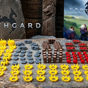 Op de afbeelding: Een verzameling Northgard bordspelonderdelen waaronder gele plastic kronen, grijze stenen fiches, bruine houten cilinders, rode voedselfiches en kleine mandjes gevuld met rode bessen, gerangschikt op een getextureerd houten oppervlak.