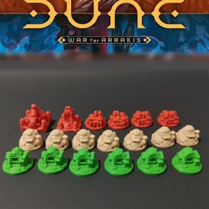 Könnte beinhalten: Eine Sammlung von Miniatur-Spielfiguren für das Brettspiel Dune: War for Arrakis. Das Set enthält rote, beige und grüne Kunststofffiguren in Form von Gebäuden und Fahrzeugen, die in Reihen vor einem unscharfen Spielkarton angeordnet sind.