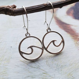 May include: Silver earrings with a circle design featuring a wave cutout.