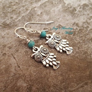 May include: Silver owl earrings with turquoise beads. The owls have detailed wings and a floral design.