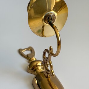 May include: A vintage brass bottle opener and corkscrew combination. The opener features a bottle cap remover, a corkscrew, and a decorative handle. The brass has a polished finish, reflecting light. The design is ornate and classic.