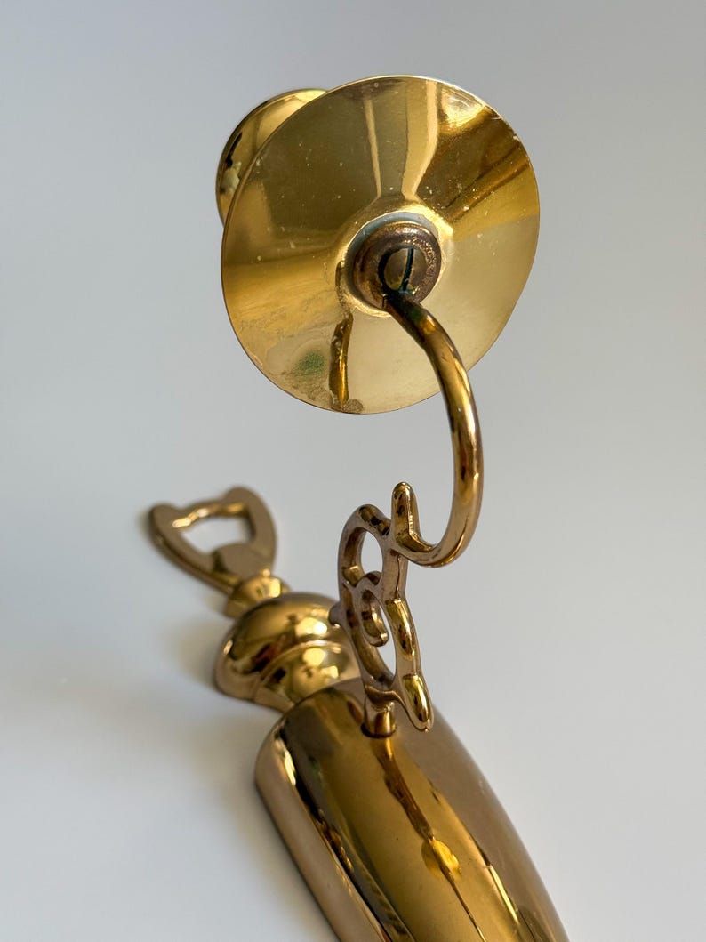 May include: A vintage brass bottle opener and corkscrew combination. The opener features a bottle cap remover, a corkscrew, and a decorative handle. The brass has a polished finish, reflecting light. The design is ornate and classic.