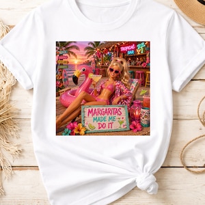 May include: White t-shirt featuring a graphic of a doll in a tropical setting, holding a margarita. The doll is lounging near a pink flamingo float. The sign reads "Margaritas Made Me Do It."