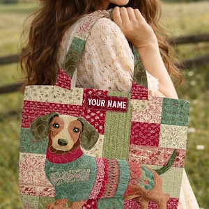 May include: A patchwork tote bag featuring a dachshund wearing a sweater. The bag has a red, green, and cream color scheme with the text "YOUR NAME" on a label. The bag is carried over the shoulder.