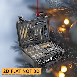 May include: A black, rectangular, hard-shell carrying case ornament featuring a foam-lined interior filled with various metal lock picking tools, tension wrenches, keys, and a small bottle of lubricant. The text Custom Name is printed on the front.