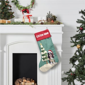May include: A Christmas stocking with a red cuff and the text "CUSTOM NAME". The body of the stocking is teal with a dog wearing a Santa hat and a Christmas tree design. A gold star is at the top of the tree.