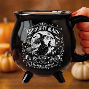 May include: A black ceramic cauldron-shaped mug featuring a white graphic of a witch on a broomstick with a cat against a full moon. The text reads MIDNIGHT MAGIC, WITCHES NEVER SLEEP, and HALLOWEEN FOREVER. The mug has three small feet.